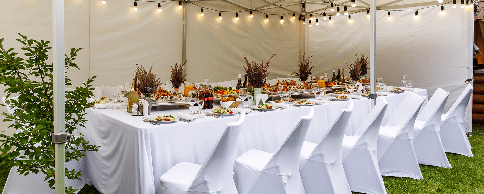 Ein weißes Zelt mit einem festlich gedeckten Tisch für eine Dinnerparty